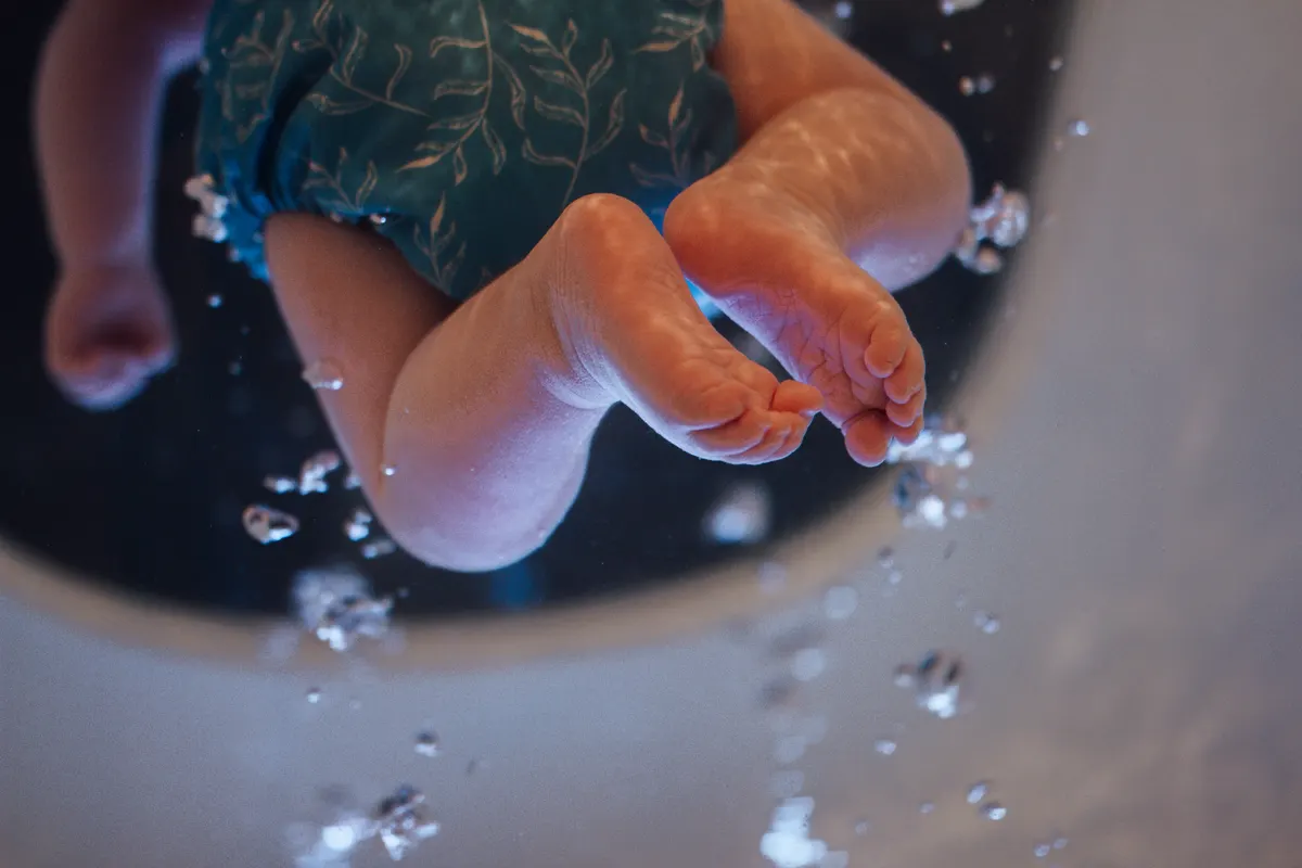 Kleine Babyfüße im Wasser, umgeben von aufsteigenden Luftblasen