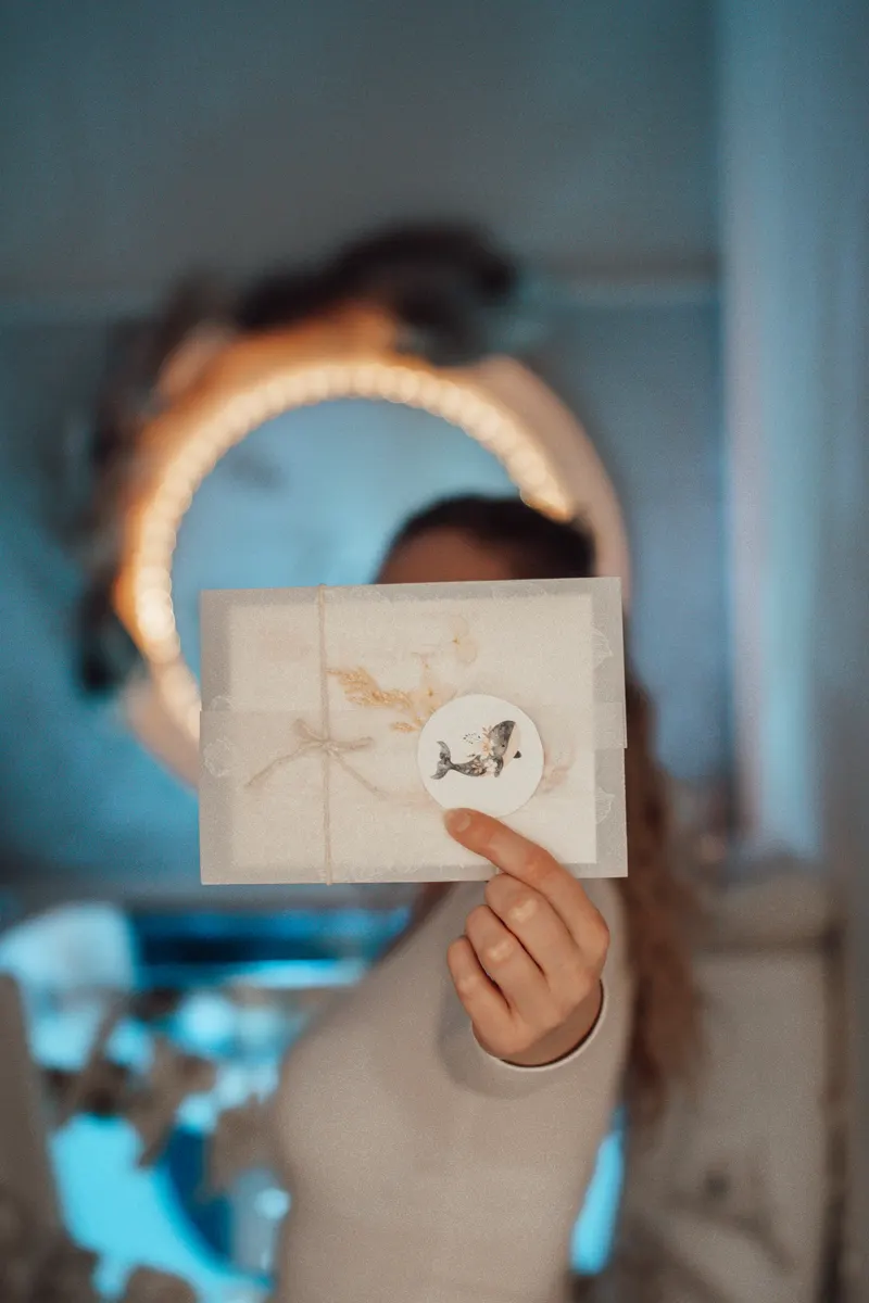 Julia hält einen liebevoll verpackten Little-Lagoon-Geschenkgutschein vor dem beleuchteten Spa-Logo