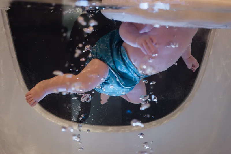 Unterwasseransicht eines strampelnden Babys im Floating-Becken