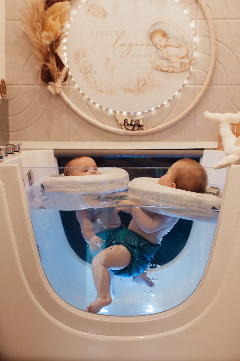Zwei Babys floaten gemeinsam mit Schwimmringen im Becken – der Doppelfloat für Besties und Zwillinge